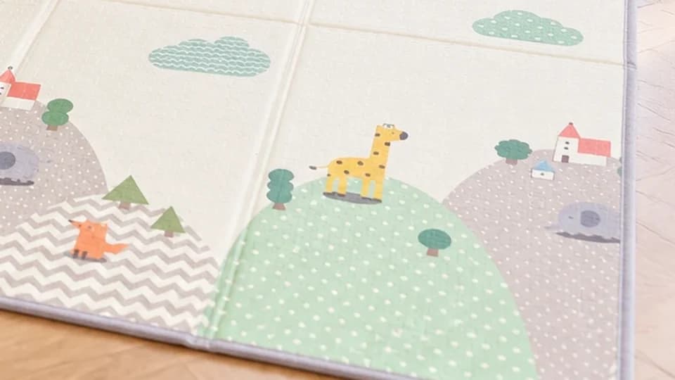 Coin du tapis déplié : collines, girafe, renard et liseré gris